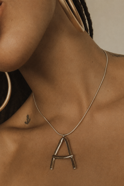 Model wearing the Celestial Imprint initial necklace in gold on a snake chain