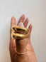 Gold ring band on a hand against a neutral background