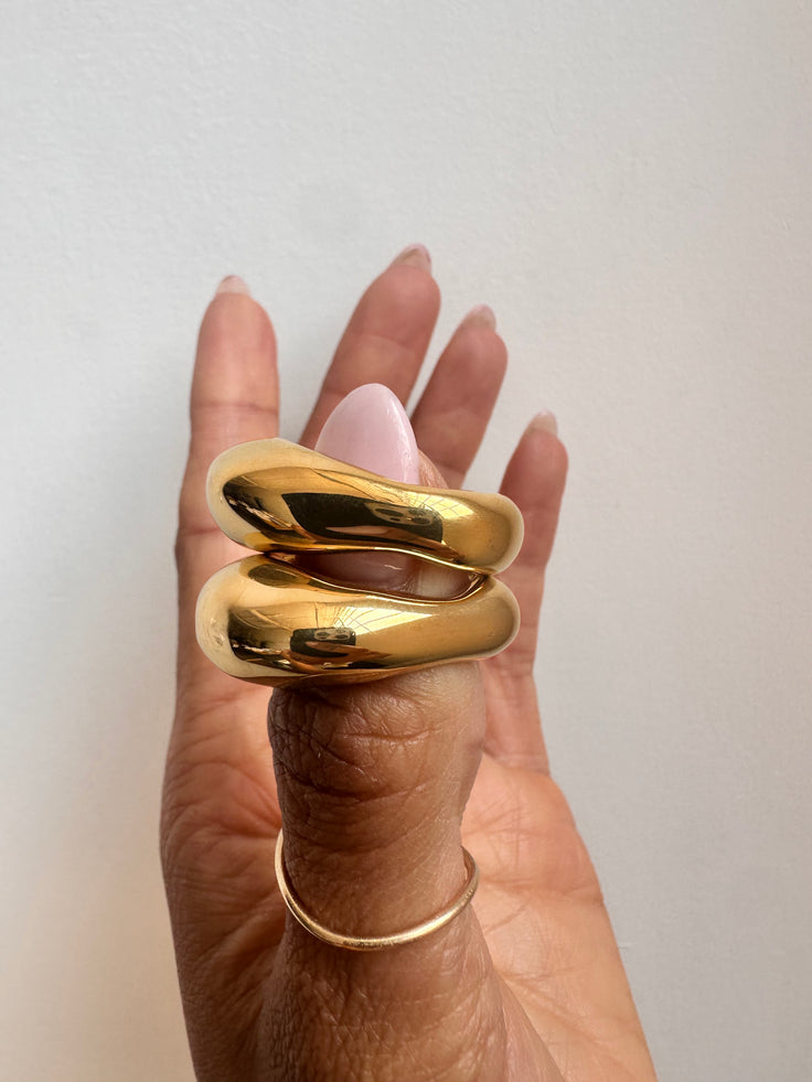 Gold ring band on a hand against a neutral background